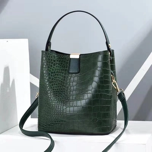 Detail of dark green crocodile texture bucket bag with elegant golden metal clasp hardware
