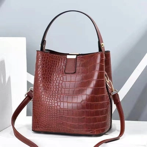 Brown crocodile embossed bucket bag with gold metal clasp and adjustable shoulder strap