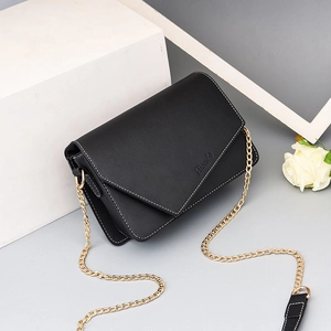 Minimalist black leather crossbody bag with white stitching and gold chain strap