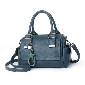 Detail of dark teal Boston bag showing lychee grain texture and star charm attachment