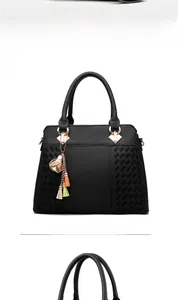 Vue de face du sac à main en cuir noir avec texture tissée et pendentif à pompon