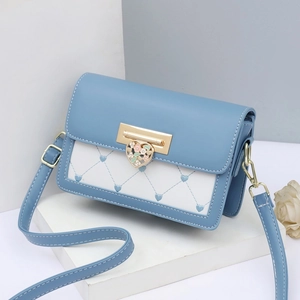 Dettaglio della borsa a tracolla blu e bianca con ricamo a cuore e chiusura dorata
