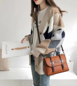 Detail of lychee textured leather crossbody bag featuring kangaroo logo and buckle