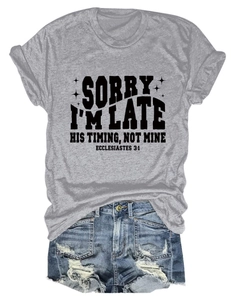 Détail d'un t-shirt gris avec texte Sorry I'm Late et un short en jean bleu délavé