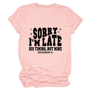 Détail de la manche retroussée et texte noir sur le t-shirt rose clair à col rond