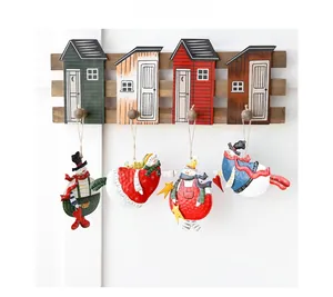 Detailed view of four vintage metal snowman ornaments hanging on a wooden house-shaped rack