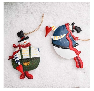 Close-up of vintage metal snowman ornaments with red scarves and hats on snowy background