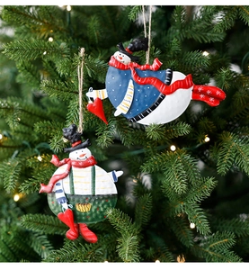 Detail of vintage metal snowman ornaments hanging on a Christmas tree with jute rope