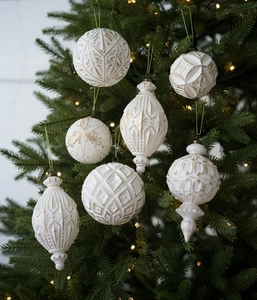Dettaglio di ornamenti natalizi vintage bianco opaco e oro su un albero festivo