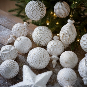 Set di decorazioni natalizie bianche e oro con finitura opaca su sfondo innevato