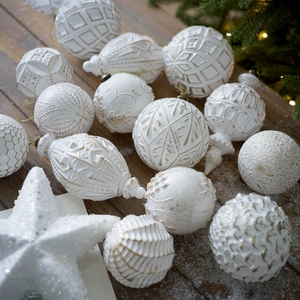 Dettaglio di ornamenti natalizi bianco perla e oro su una superficie di legno innevata