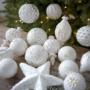 Set di decorazioni natalizie bianco e oro con varie forme su un albero festivo