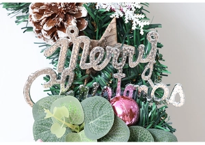 Dettaglio della ghirlanda di Natale con pigne innevate, sfere rosa e scritta Merry Christmas
