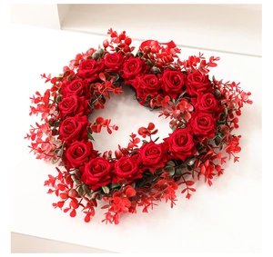Close-up of a dense red rose wreath with silk fabric petals and green foliage detail