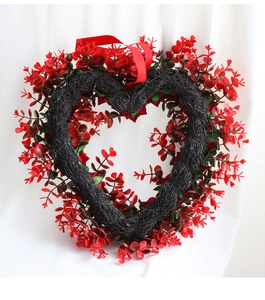 Close-up of a red heart-shaped rose wreath with a ribbon for Valentine party decor