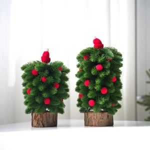 Detail of two mini Christmas trees with red hats, plush balls and natural wood base