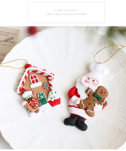 Details von Lebkuchenhaus und Weihnachtsmann Harzanhängern mit goldenen Schnüren auf Teller