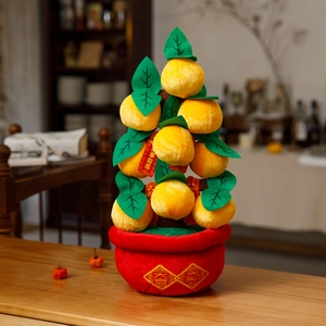 Close-up of plush orange tree decor with Good Luck tags on a wooden tabletop