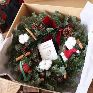 Christmas wreath gift box with pine cones, cotton, cinnamon sticks and red velvet bow