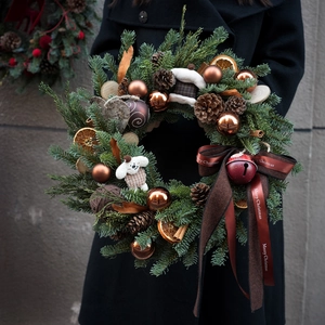 Detail of Christmas wreath with pine cones, orange slices, and a plush dog ornament