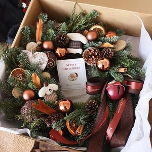 Detail of Christmas wreath gift box with pine cones, cinnamon sticks and Merry Christmas ribbon