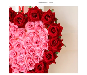 Détail de pétales de roses artificielles rouges et roses disposés en couronne de cœur