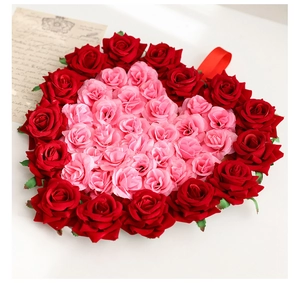 Détail de la couronne de roses artificielles rouges et roses avec ruban en soie rouge