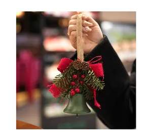 Close-up of forest green Christmas bell ornament with pine needles and a red bow