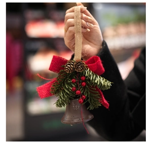 Detail of Christmas bell ornament with red burlap bow, pine needles and natural pinecones