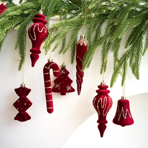 Detalle de adornos navideños de terciopelo rojo con purpurina dorada en una rama verde