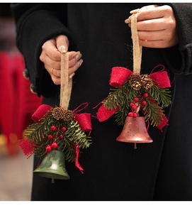 Macro view of Christmas bells with pine cones, red berries and burlap bow decoration