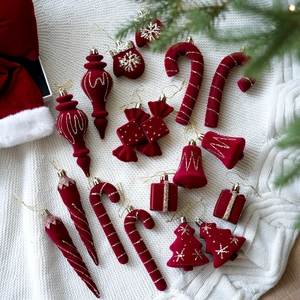 Detalle de adornos navideños de terciopelo rojo con purpurina dorada sobre punto blanco