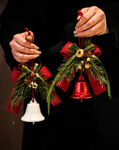 Detalle de campanas de Navidad con lazos de arpillera, piñas y bayas rojas