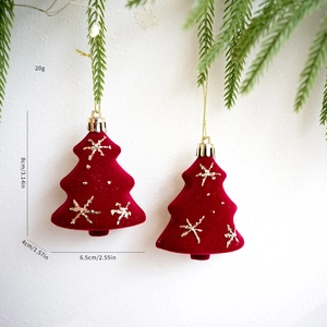 Detalle de adornos de árbol de Navidad en terciopelo rojo con copos dorados y pino verde