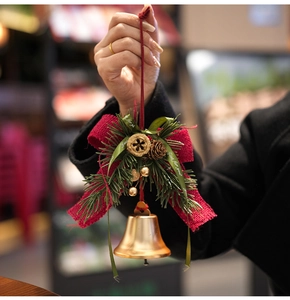 Detalle de campana de Navidad con lazo rojo, piñas y cinta con texto Just For You