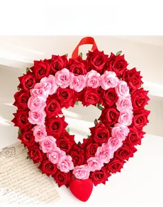Close-up of heart-shaped wreath with red and pink roses and satin ribbon for decor