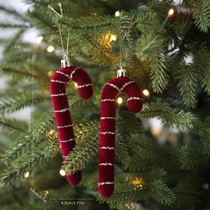 Detalle de bastones de caramelo rojos flocados con rayas doradas colgados en el árbol
