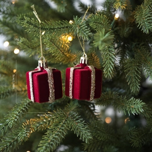 Detalle de mini cajas de regalo rojas flocadas con cintas doradas colgadas en el árbol de Navidad