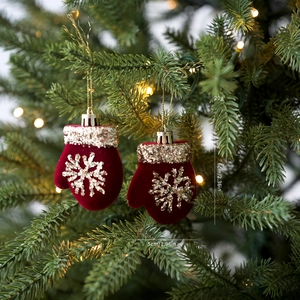 Detalle de guante navideño rojo aterciopelado con lentejuelas doradas en el árbol