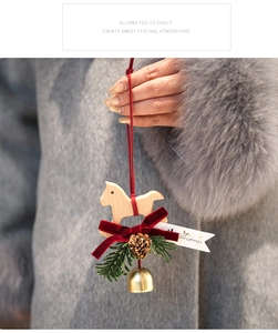 Detail of wooden rocking horse Christmas ornament with red velvet bow and pine cone