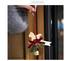 Close-up of wooden rocking horse ornament with red velvet bow and pine needles