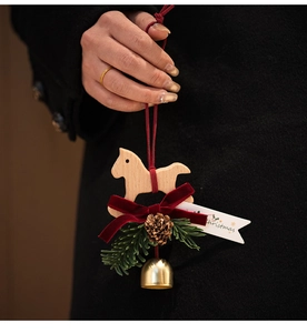 Detail of Christmas wooden horse ornament with red velvet bow and pine cones