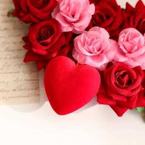 Valentinstag Herz-Kranz mit roten und rosa Rosen auf einem Vintage-Briefhintergrund