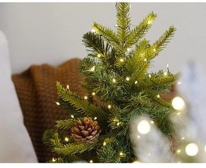 Détail d'un mini sapin de Noël de table avec lumières LED chaudes et pommes de pin