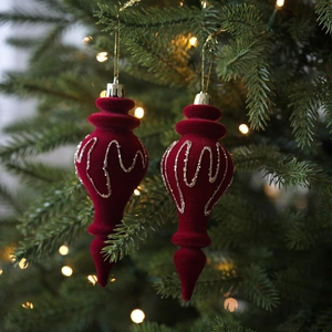 Adorno navideño rojo aterciopelado con purpurina dorada sobre fondo festivo cálido