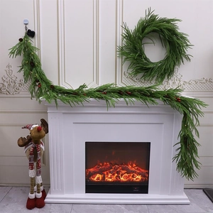 Green Christmas garland and wreath with pine cones and red berries on a white fireplace