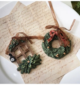 Detalle de adornos navideños vintage de resina con ventana, corona y cintas decorativas