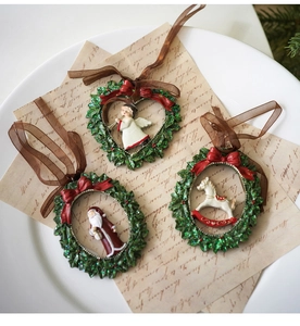 Detalle de adornos navideños de resina con ángel y Papá Noel sobre guirnaldas de acebo