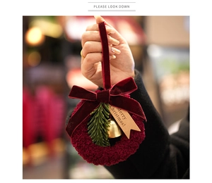 Detail of red velvet Christmas wreath with gold bell, pine needles and Merry Christmas tag