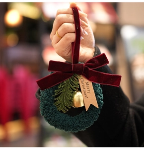 Detailed view of mini Christmas wreath pendant with red bow, gold bell and Merry Christmas tag